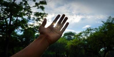 Hand, die versucht, die Sonnenstrahlen zu berühren foto