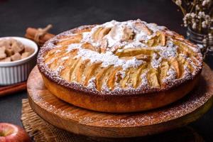 Apfelkuchen mit frischen Früchten auf einem Holztisch foto