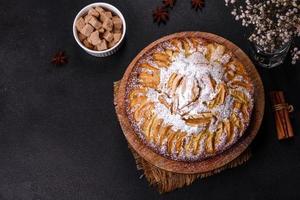 Apfelkuchen mit frischen Früchten auf einem Holztisch foto