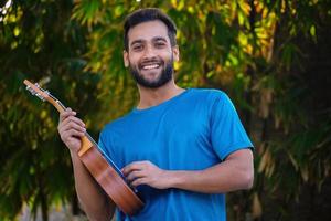Junge mit Ukulele ein Musikinstrument hübsches indisches Musikerbild foto
