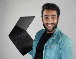 Mann mit einem lächelnden Laptop, der die Kamera beobachtet foto