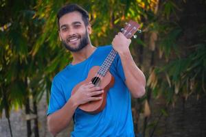 Junge mit Ukulele ein Musikinstrument hübsches indisches Musikerbild foto