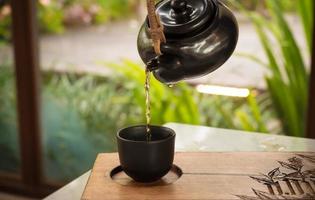 Gießen Sie traditionellen chinesischen oder japanischen Tee von Hand aus einem Tontopf