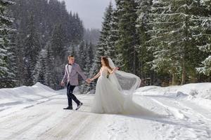 der bräutigam führt seine braut an der hand zu einer einsamen alten buche. Winterhochzeit. Platz für ein Logo. foto