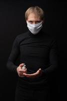 Ein Mann in einer medizinischen Maske zeigt, wie man seine Hände mit einem Antiseptikum behandelt. Coronavirus Schutz. foto