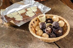 Pralinen und Schokolade in einem Korb auf einem Holztisch foto