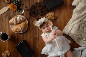 Kleine Köchin mit einem Holzlöffel bereitet das Mittagessen zu. foto