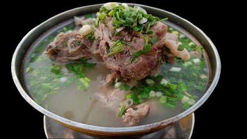 nahaufnahme thailändisches essen, würzige schweineknochensuppe schwarzer hintergrund foto