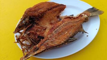köstlicher asiatischer gebratener fisch, serviert auf einem gelben tisch. thailändisches essen foto