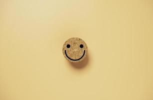 Lächeln Sie Gesicht auf Kreisholzblock auf orangefarbenem Hintergrund für glückliches Denkkonzept. foto