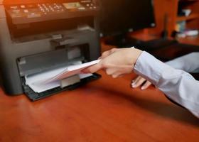 Die menschliche Hand lädt das Papier in das Druckerfach foto