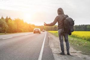 Ein Anhalter erwischt ein Auto auf der Straße foto