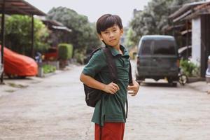 asiatischer elementarer junge, der vor der schule vor der kamera posiert foto