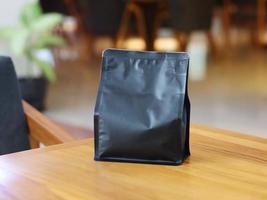 Foto einer stehenden Beutelkaffeeverpackung auf dem Cafétisch. geeignet für Mock-up-Etikettenaufkleber, Verpackungsaufkleber für Kaffeevarianten usw.