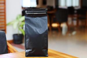 Foto einer Kaffeeverpackung, die Beutelgröße 1 kg auf dem Cafétisch steht. geeignet für Mock-up-Etikettenaufkleber, Verpackungsaufkleber für Kaffeevarianten usw.