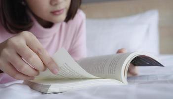 junge frau, die buch auf bett liegt und liest. foto