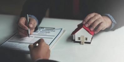 der immobilienmakler erklärt den kunden den hausstil, die zu kontakt kommen, um das hausdesign und den kaufvertrag zu sehen. in einem modernen Büro foto