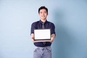 Porträt des jungen asiatischen Geschäftsmannes mit Laptop auf blauem Hintergrund foto
