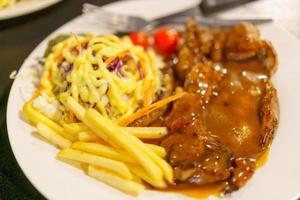 Steak mit Sauce mit Salat und Pommes frites foto