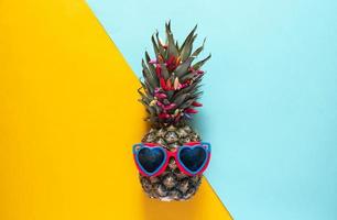 eine smarte ananas in sonnenbrillen und hellen perlen. minimales konzept, sommerliche tropische ananas.