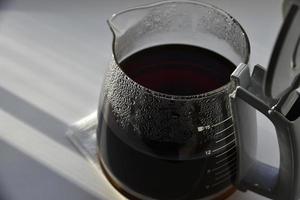 Kaffeekanne aus Glas mit einem Getränk auf weißem Hintergrund foto