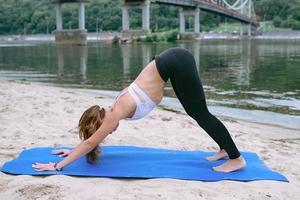 Junge fitte Frau in Sportbekleidung in verschiedenen Yoga-Asanas im Freien am Strand am Fluss. yoga- und sportkonzept foto