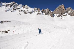 skifahrer in sportbekleidung skifahren auf schneebedeckter hügellandschaft gegen berg foto