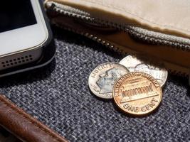 us-dollar-münzen, die mit dem smartphone außerhalb der brieftasche platziert werden. foto