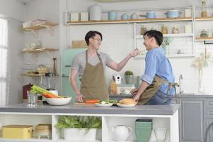 junges lächelndes homosexuelles paar, das zusammen in der küche zu hause kocht, lgbtq und diversitätskonzept. foto