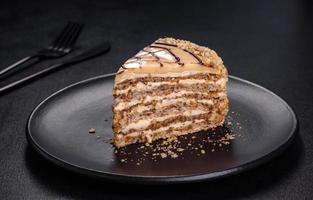 Esterhazy-Kuchen, geschnitten auf schwarzem Teller, Nahaufnahme. Süßes Feinkostdessert mit Mandel-Baiser-Teig und Buttercreme foto