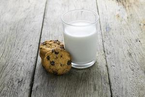 Plätzchen und ein Glas mit Milch auf Holztisch foto