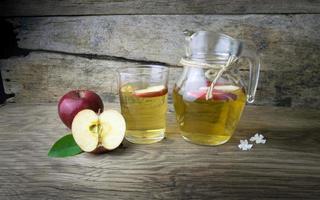 Apfelsaft und Äpfel auf einem Holztisch foto