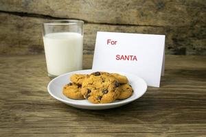 Kekse und ein Glas Milch mit einer weißen Note für Santa foto