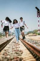 Gruppe fröhlicher Teenager, die mit Glück auf der Bahnstrecke laufen foto