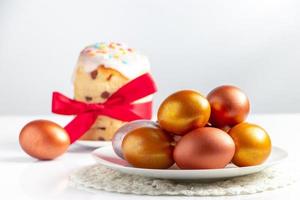 Osterkuchen mit süßem Zuckerguss und goldenen Eiern auf weißem Teller. foto