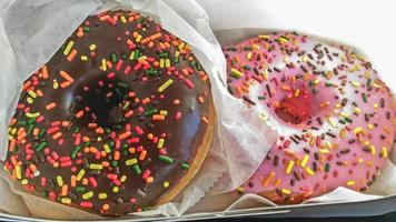 zwei süße bunte donuts mit leckerer glasur, verpackt und servierfertig foto