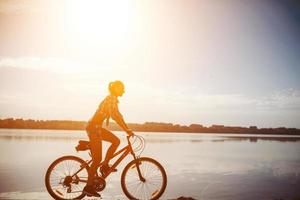 Frau auf einem Fahrrad in der Nähe des Wassers foto