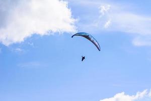 Mann auf einem Fallschirm, der in den klaren Himmel fliegt foto