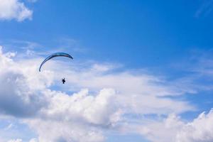 Mann auf einem Fallschirm, der in den klaren Himmel fliegt foto