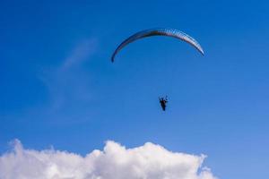Mann auf einem Fallschirm, der in den klaren Himmel fliegt foto
