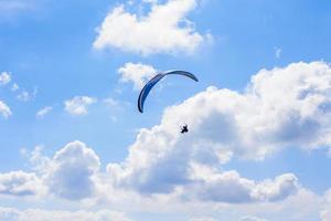 Mann auf einem Fallschirm, der in den klaren Himmel fliegt foto