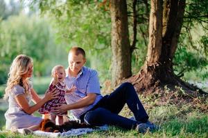 Glückliche Familie geht im grünen Sommerpark spazieren foto