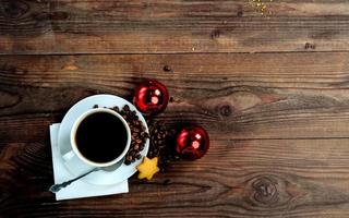 eine tasse kaffee, ein sternplätzchen und zwei rote weihnachtskugeln. weihnachtskaffeegetränk. foto