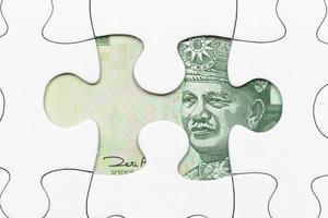 malaysische Ringgit-Banknote versteckt unter Puzzle-Finanzkonzept foto