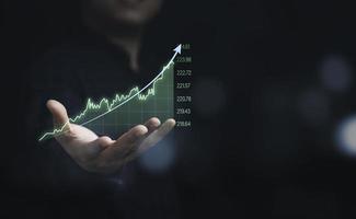 geschäftsmann, der virtuelles technisches diagramm und diagramm für analyseaktienmarkt, technologieinvestitionen und wertinvestitionskonzept hält. foto