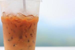 Eiskaffee mit Strohhalm im Plastikbecher mit Naturhintergrund foto