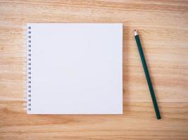 Draufsicht des Notizbuchs mit weißem Einband und Bleistift auf braunem Holzschreibtisch foto