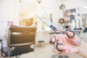 friseur hält schere mit salonschönheitshintergrund foto