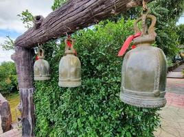 Gruppe von alten glücklichen goldenen Glockenringen, die an der Holzstange hängen. thailand buddismus tradition tempel symbol. foto