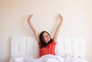 das mädchen sitzt auf dem bett und streckt sich, die frau ist aufgewacht foto